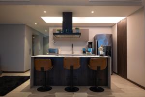 a kitchen with a blue island with three bar stools at Condo in Bucerías Beachfront Narval Norte in Bucerías