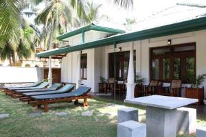 a row of chaise lounges in front of a house at Lohas Beach Resort Villa in Kalutara