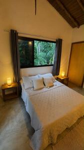 a bedroom with a large bed and a window at Suíte em Trindade, Praia Brava, na Mata in Paraty