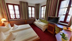 a hotel room with two beds and a flat screen tv at Hotel Augsburger Hof in Augsburg