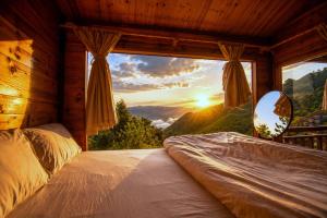 a bed in a room with a view of the sunset at Mống Vàng Retreat Tà Xùa in Sơn La