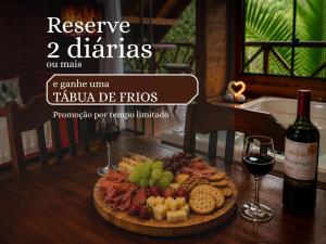 a plate of food on a table with wine and wine glasses at Cabana com Cachoeira Privativa in Imaruí