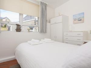 a white bedroom with a white bed and a window at 4 Thornlea Mews in Kingsbridge