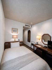 a bedroom with a bed and a desk and a mirror at Kuretake-Inn Kakegawa in Kakegawa +18 photos
