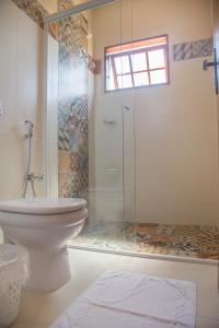 uma casa de banho com uma cabina de duche em vidro e um WC. em Vila Chico em São Lourenço