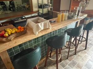 a kitchen with a counter with a bowl of fruit and stools at Shika Lodge Izu in Ito +1 photo