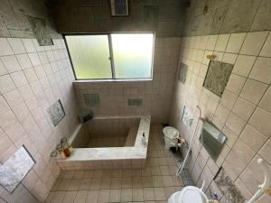 a tiled bathroom with a tub and a toilet at Shika Lodge Izu in Ito