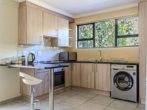 a kitchen with wooden cabinets and a washer and dryer at Serene Pastures in Midrand