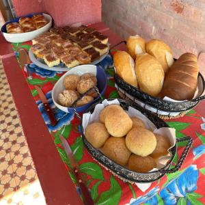 a table topped with baskets of bread and pastries at Pousada & Chalés Quinta da Nascente - Serra da Canastra in Delfinópolis