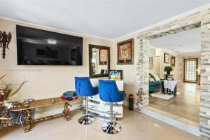 a living room with a television and blue chairs at Luxury Waterfront Villa, With Private Hot Tub, Beachs, Aventura Mall Casinos, Restaruants in Hallandale Beach