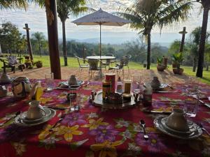 a table with plates and utensils on top at Pousada & Chalés Quinta da Nascente - Serra da Canastra in Delfinópolis
