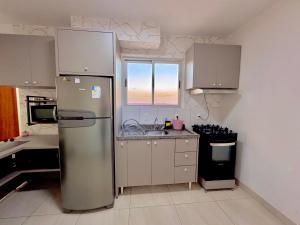 a kitchen with a stainless steel refrigerator and a stove at Apê confortável com garagem e espaço de trabalho in Cuiabá