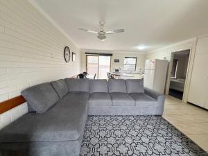 a living room with a gray couch and a kitchen at Cameo Court 1 in South West Rocks