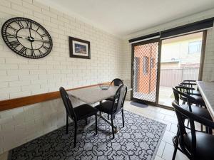 a dining room with a table and a clock on the wall at Cameo Court 1 in South West Rocks +5 photos
