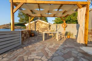 a patio with a table and chairs under a wooden pergola at Ambelos, Lesvos Beach House in Koustáros