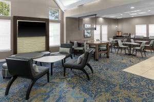 a waiting room with tables and chairs and a bar at Residence Inn Mystic Groton in Mystic