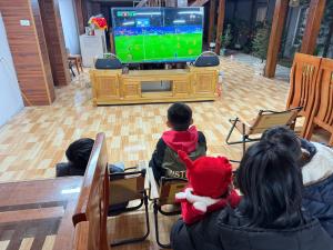 a group of children playing a video game on a television at Honey Homes Cô Tô in Đảo Cô Tô