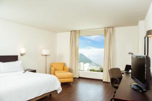 a hotel room with a bed and a chair and a window at Fiesta Inn Monterrey Tecnologico in Monterrey