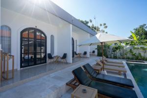 a patio with a pool and chairs and an umbrella at Majestic Balangan in Uluwatu