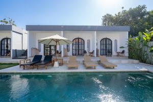 a pool with chairs and an umbrella next to a house at Majestic Balangan in Uluwatu