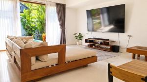 a living room with a couch and a flat screen tv at Tropical Villa with Swimming Pool in Selong Belanak