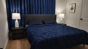 a bedroom with a blue bed and two lamps at TNC Stays Luxurious Modern Suite Seton Calgary South in Calgary +26 photos