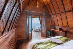 a bedroom with a bed in a room with the ocean at Suwehan Rey Cliff House in Nusa Penida