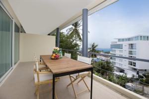 a balcony with a wooden table and chairs on a building at Woodbridge Property at Karon Butterfly in Karon Beach