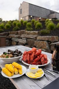 a table with three plates of seafood and other foods at Cedar - Luxury Oceanview Cottage with Hot Tub & Private Beach Access near Cabot Trail in Chimney Corner
