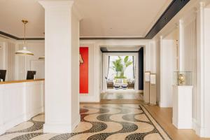 a hallway with white columns and a rug on the floor at MiM Sotogrande member of Meliá Collection in Sotogrande
