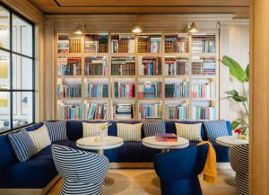 a library with a blue couch and tables and books at MiM Sotogrande member of Meliá Collection in Sotogrande