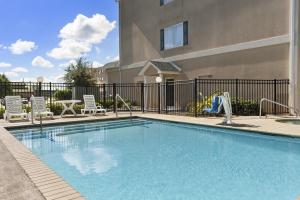 a swimming pool with chairs and a playground at Country Inn & Suites by Radisson, Saraland, AL in Saraland