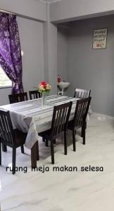 a dining room table with chairs and a vase of flowers on it at Qiffah Homestay in Kuala Terengganu