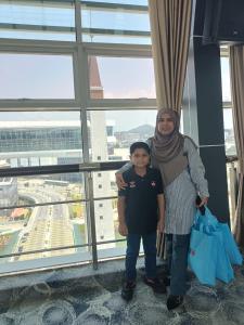 a woman and child standing in front of a window at Qiffah Homestay in Kuala Terengganu