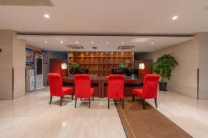 a lobby with a table and red chairs at Greenland Mansion in Shanghai