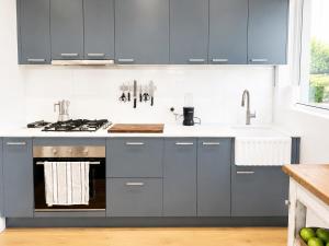 a kitchen with blue cabinets and a sink at Unique beach flat with own carpark area in Freshwater