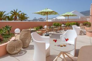 a patio with white chairs and tables and umbrellas at SOL by Meliá Sun Beach Apartamentos in Adeje