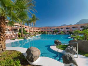 a large swimming pool with palm trees and a building at SOL by Meliá Sun Beach Apartamentos in Adeje