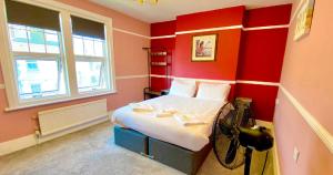 a bedroom with red walls and a bed with white sheets at The Loriston in Eastbourne