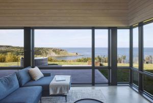 a living room with a couch and a view of the ocean at Birch - Luxury Oceanview Cottage with Hot Tub & Private Beach Access near Cabot Trail in Chimney Corner
