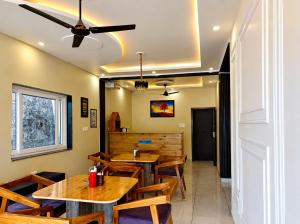 a restaurant with wooden tables and chairs and a ceiling fan at The Boho Shantii Stays in Bhīm Tāl
