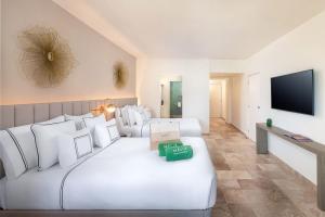 a hotel room with a large white bed and a flat screen tv at Meliá Casa Maya Cancún in Cancún