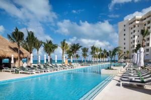 a swimming pool with chaise lounge chairs and the ocean at Meliá Casa Maya Cancún in Cancún
