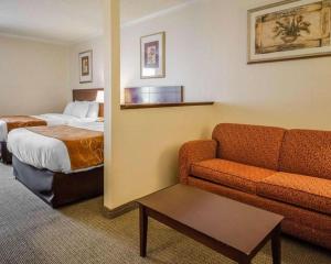 a hotel room with a couch and a bed at Quality Suites Jeffersonville - Louisville North in Clarksville