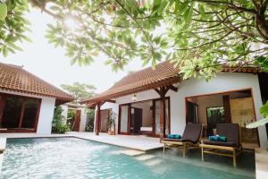 a villa with a swimming pool and two chairs at Aria Exclusive Villas & SPA in Seminyak