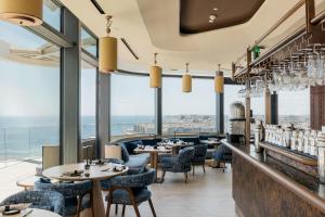 a restaurant with tables and chairs and large windows at ME by Meliá Malta in St. Julianʼs