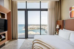 a hotel room with a bed and a large window at ME by Meliá Malta in St. Julianʼs