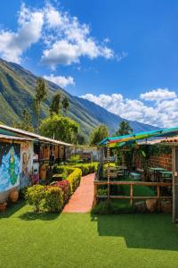 a garden with green grass and buildings with mountains in the background at Valle verde, Hostel & camping in Urubamba