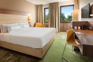 a hotel room with a large bed and a desk at Meliá Düsseldorf in Düsseldorf