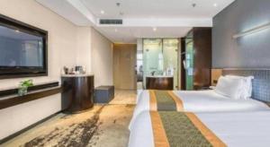a hotel room with a bed and a television at Harbin Splendent Hotel in Shuangcheng